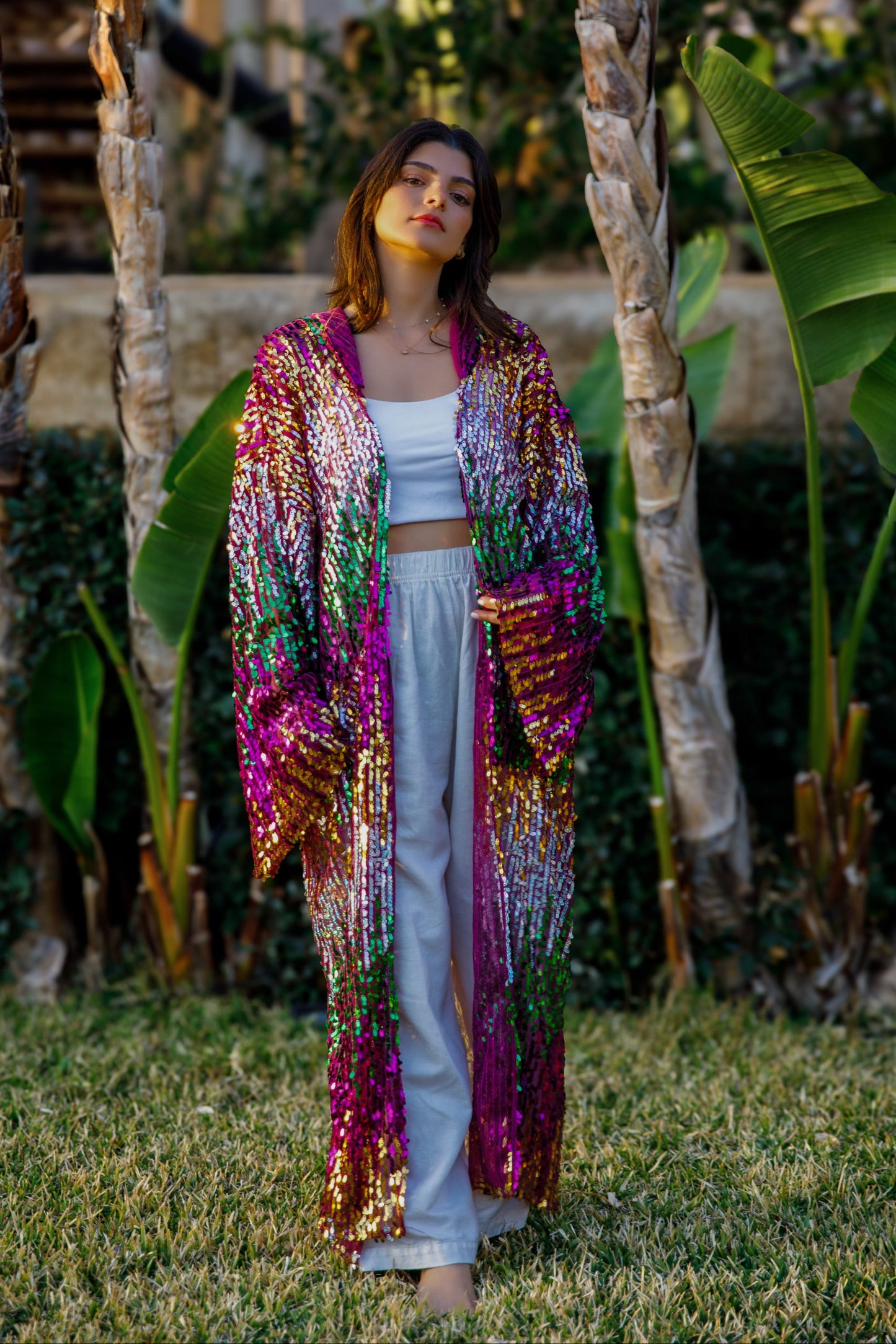 Woman wearing a colorful sequin jacket in a garden setting