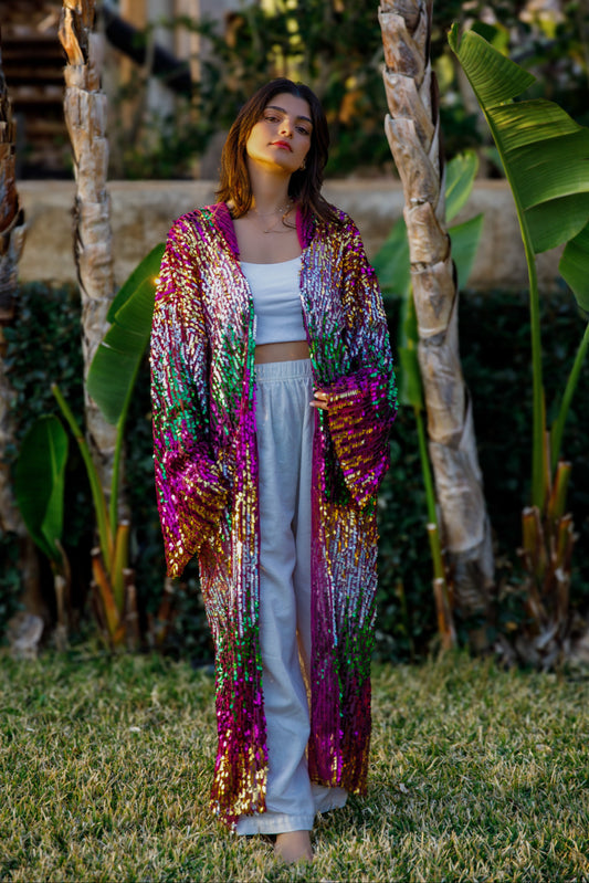 Woman wearing a colorful sequin jacket in a garden setting